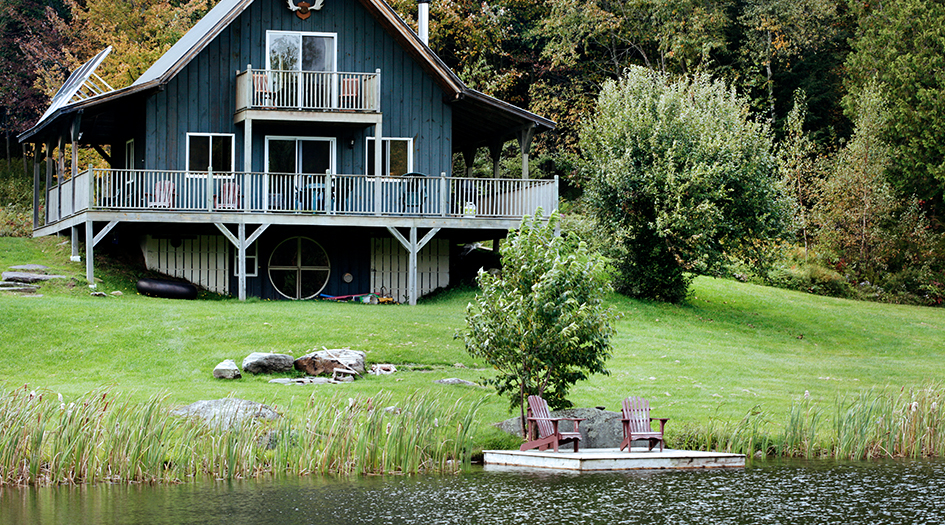 Un chalet près d’un lac où des herbes hautes bordent la rive démontrant l’une des façons de protéger la berge de l’érosion.