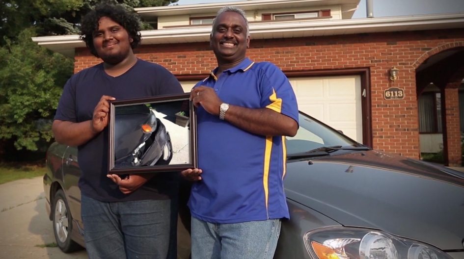 Des clients d’Economical, un père et un fils, tiennent une photo de leur voiture endommagée