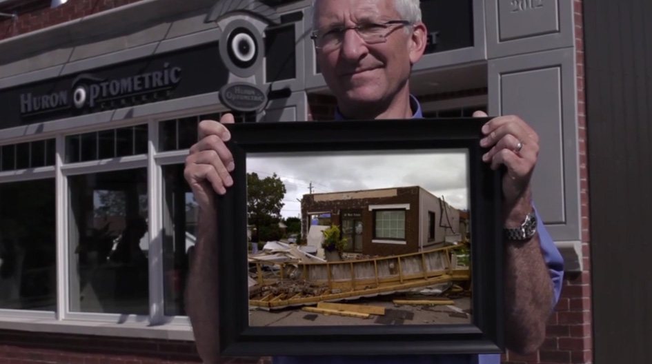 Un client d’Economical tient une photo de son entreprise endommagée par une tempête