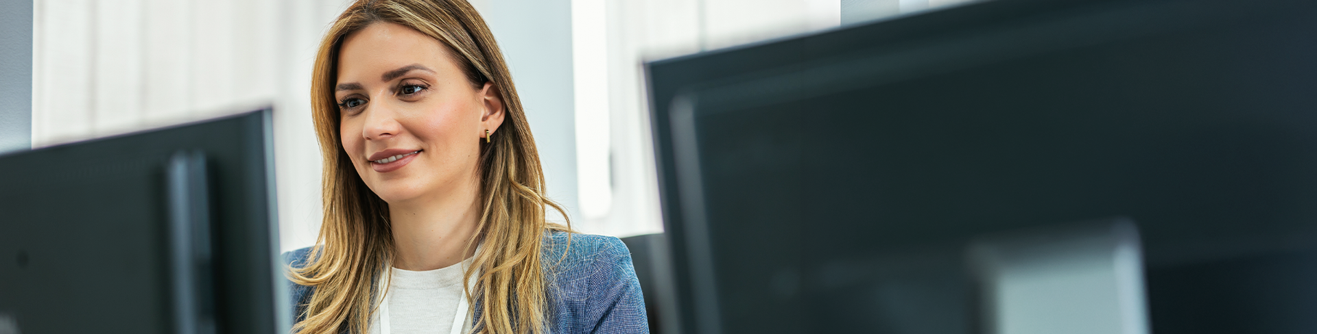 Une femme souriante qui travaille à son ordinateur dans un bureau.