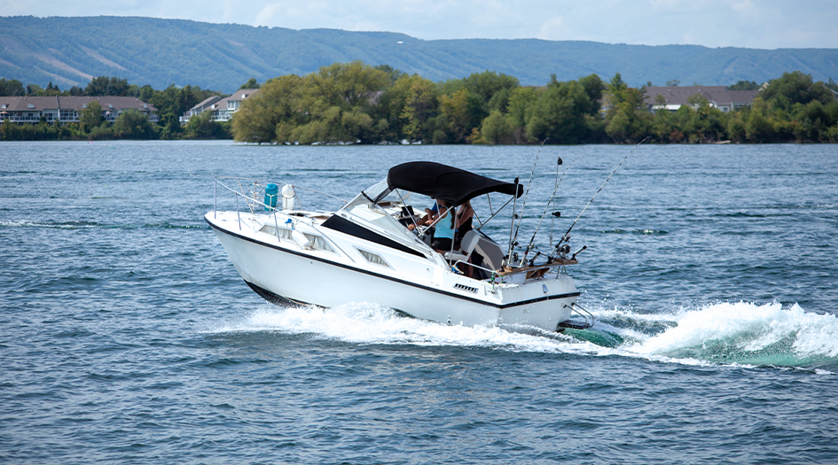 A white motorboat cruises on the water, showing you how to get your boat ready for summer