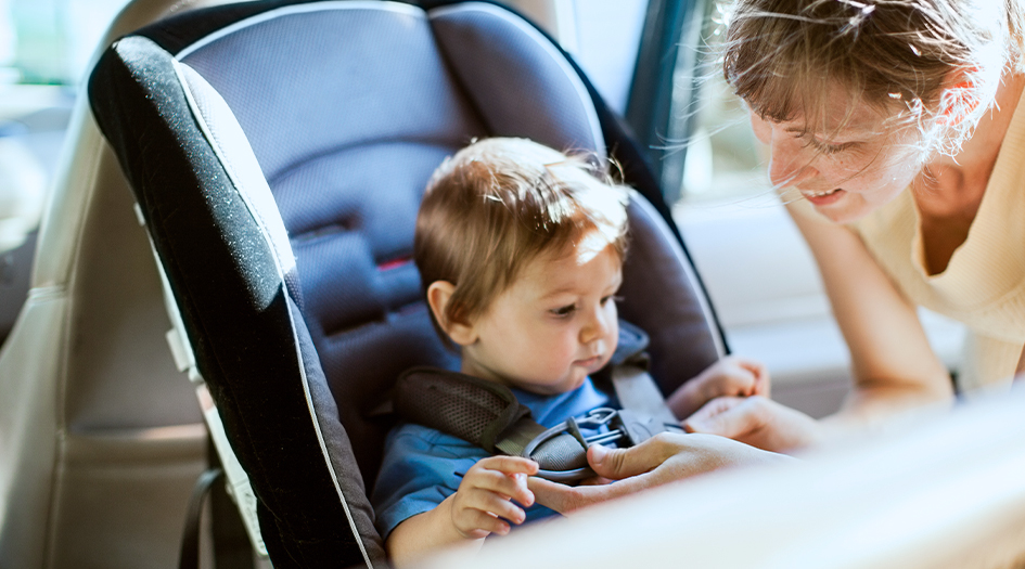 A woman buckles her child into a car seat, making sure her child's car seat keeps them safe and secure on the road