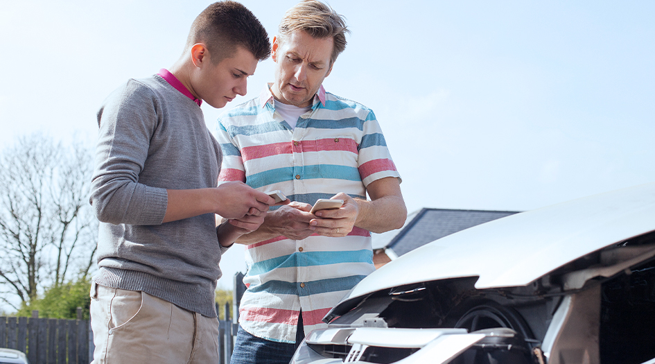 Two men share insurance information after a car accident, showing what a pink slip is used for