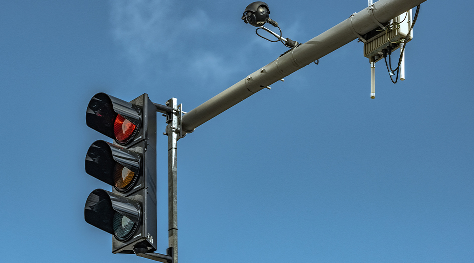 A traffic stoplight is red, with a camera mounted on it, showing you how red light cameras work