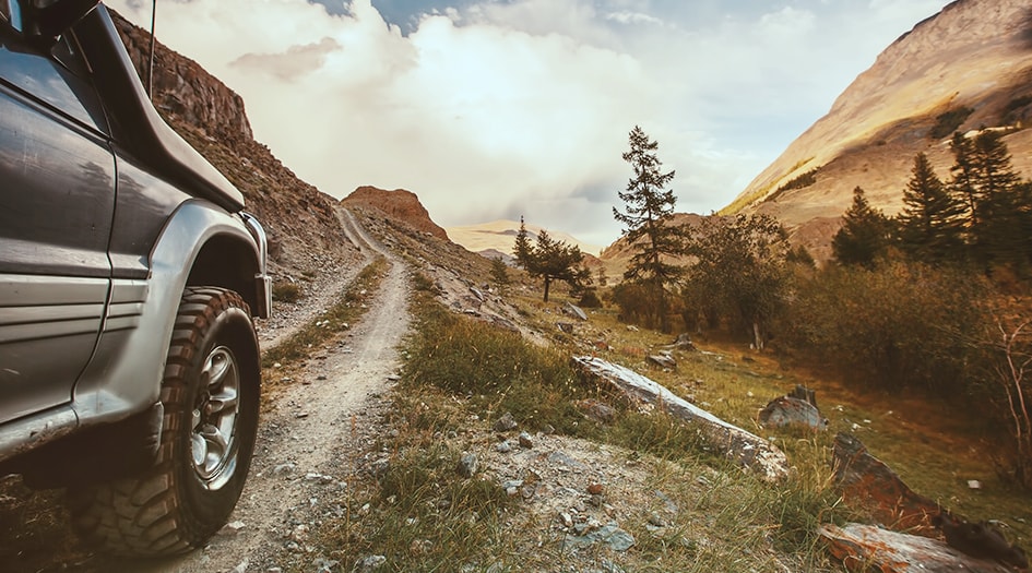 A truck drives on a bumpy gravel trail in the mountains, showing the differences between two, four and all-wheel drive