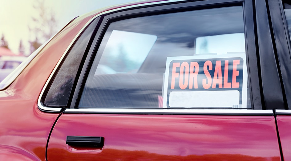 A red car has a for sale sign in the back window, showing why you should consider what car insurance you need for a used vehicle