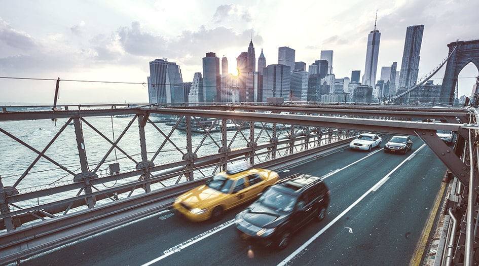 Cars cross a bridge in the city, illustrating what happens if you have Canadian car insurance and get in an accident in the United States