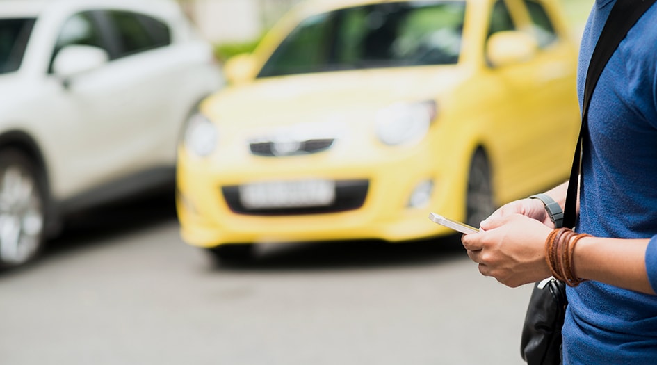 An individual looks at their phone in a parking lot, considering what to do after a hit and run accident