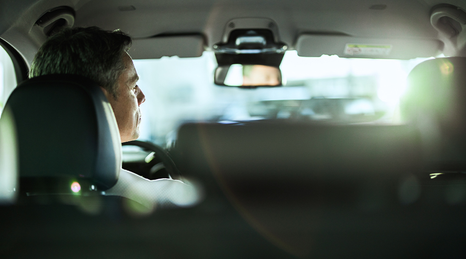 A man looks into the rearview mirror in his car as he wonders who is at fault for a collision in a parking lot