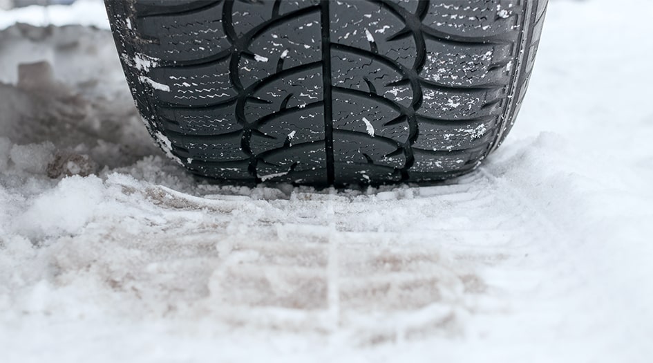 A close up of a tire on snow shows you why you need winter tires