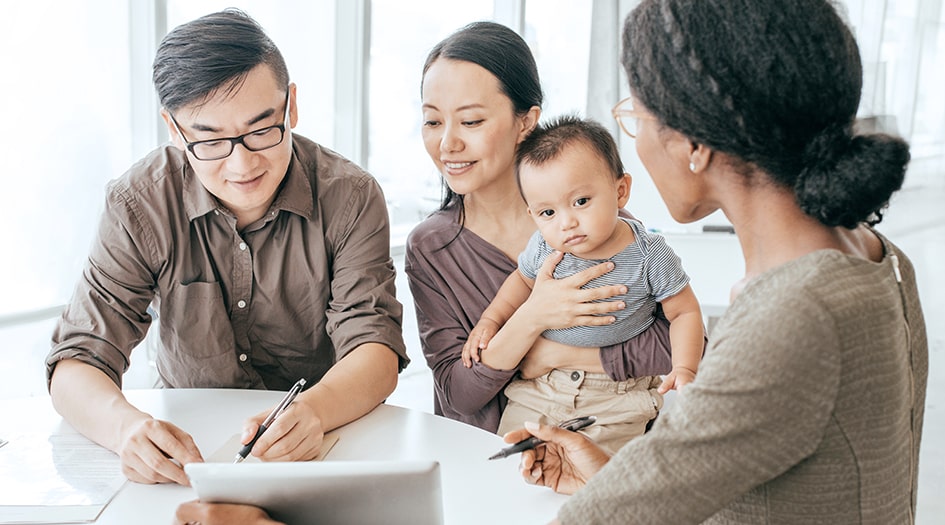 A couple sitting with a baby compare home insurance quotes with a broker