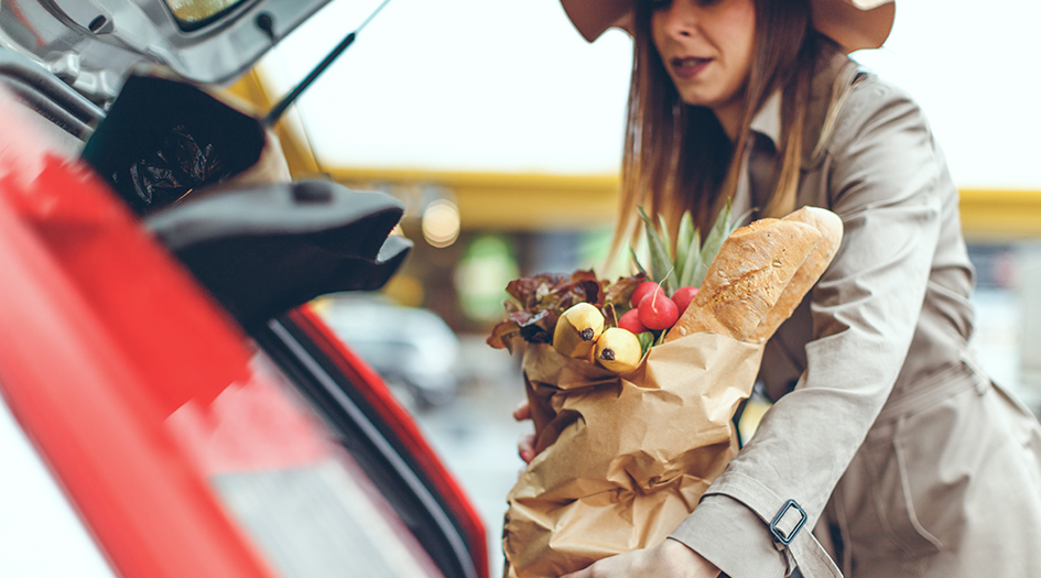 A woman loads groceries into her car's trunk, showing how you can help in your community 