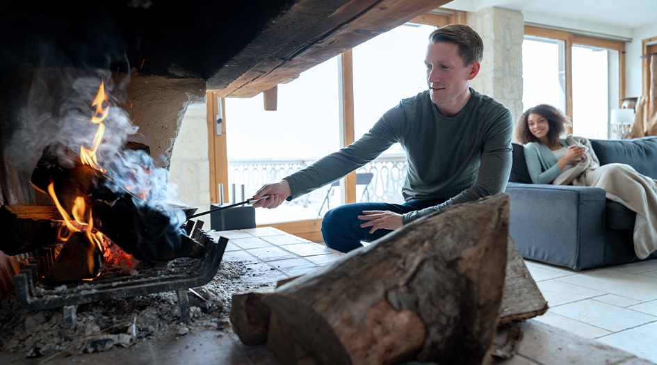 Here are 5 ways to protect your family from carbon monoxide poisoning, as shown by a man stoking a fireplace