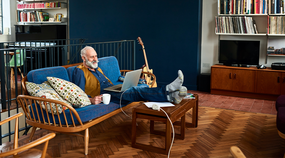 A man sits on the couch on his laptop, learning about common home insurance myths
