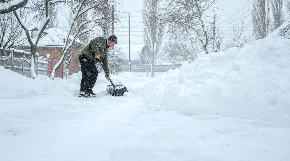 Follow these tips when shovelling snow, as shown by a man shovelling his snowy sidewalk