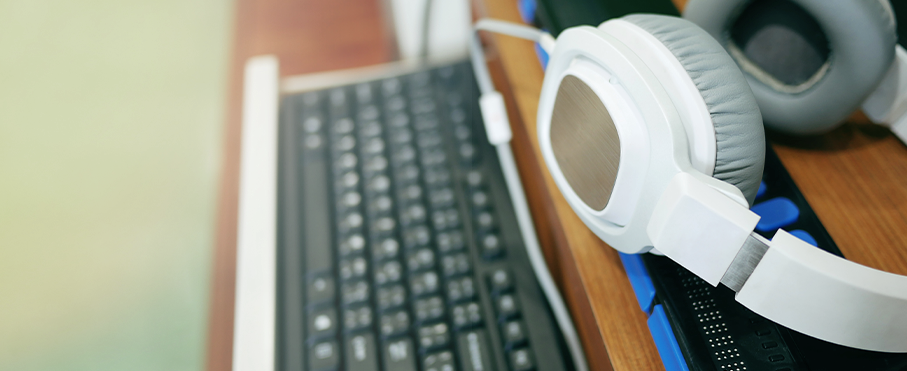 Gros plan sur un casque d'écoute blanc reposant sur un bureau à côté d'un clavier.