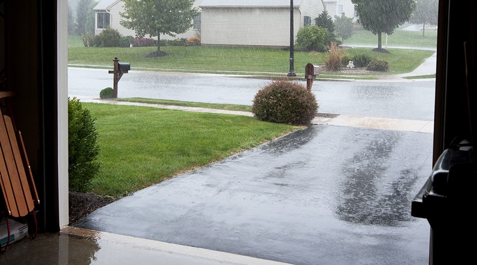 Une pluie abondante tombe sur une entrée, ce qui montre pourquoi vous devriez prévenir les dommages causés par l’eau dans votre domicile.