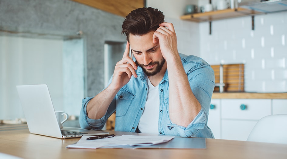 Un homme a l’air préoccupé en parlant au téléphone; il se demande s’il doit payer la franchise s’il n’est pas responsable.