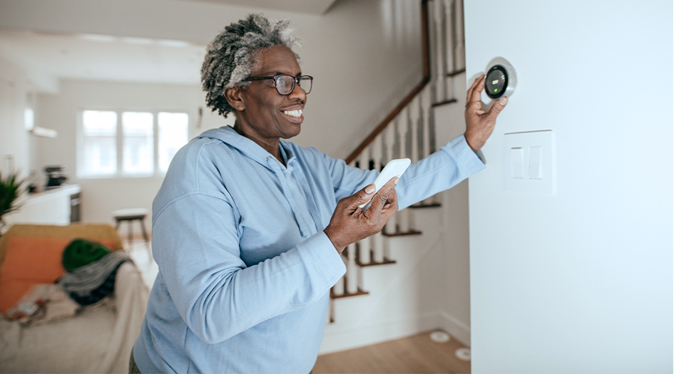 Une femme ajuste son thermostat, illustrant comment des rénovations peuvent diminuer le coût de l’assurance habitation.