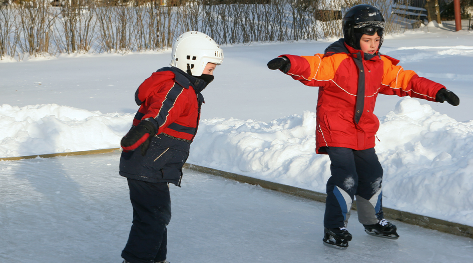 Deux enfants s’amusent sur une patinoire, illustrant comment une patinoire dans votre touche votre assurance habitation.