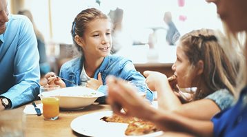 Une famille mange un repas à l’extérieur, illustrant ce qui peut être couvert par les frais de subsistance supplémentaires.