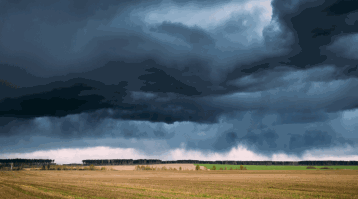 Looking out on to a field with storms on the horizon
