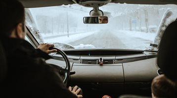 Un homme conduit sa voiture dans la neige pour illustrer ce qu’il faut faire avant, pendant et après une tempête.