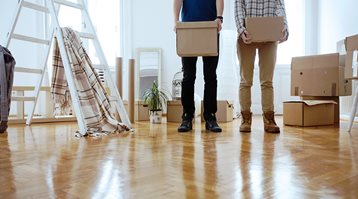 Two men hold cardboard boxes in a room of household items that tenant insurance can help protect in the event of an emergency