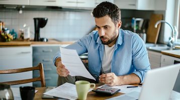 A man reads paperwork at his laptop, as he gets the lowdown on insurance deductibles